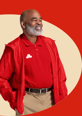 A bearded State Farm agent in red polo shirt and pullover smiles.