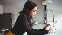 A woman in a black sweater checks the status of her claim on on her ipad.